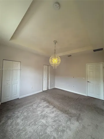 a view of an empty room with a chandelier fan