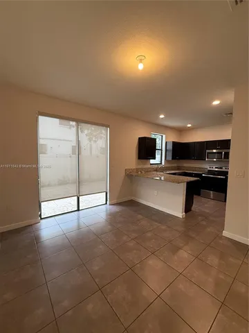 a view of kitchen with stainless steel appliances granite countertop a refrigerator and a sink