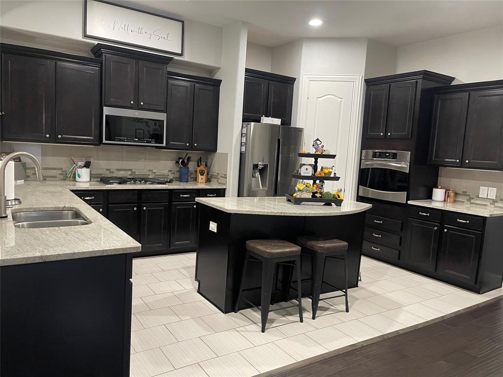 a kitchen with stainless steel appliances kitchen island granite countertop a sink refrigerator and cabinets
