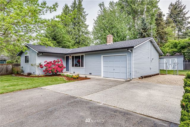 a front view of house with yard and trees all around