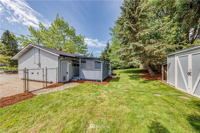 a view of backyard of house with wooden fence and large trees