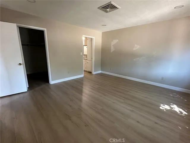 an empty room with wooden floor & closet area