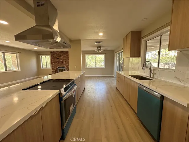 a kitchen with granite countertop a stove a sink a refrigerator and wooden floor