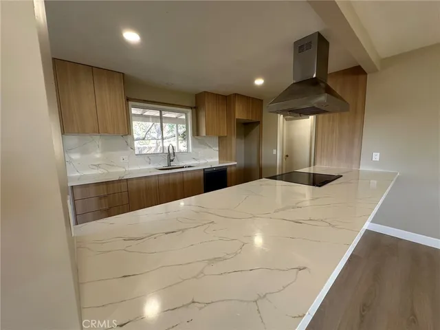 a large white kitchen with a sink and dishwasher a stove top oven with wooden floor