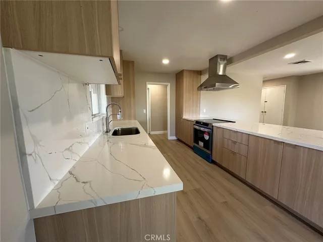 a large kitchen with a large counter top space a sink stainless steel appliances and cabinets