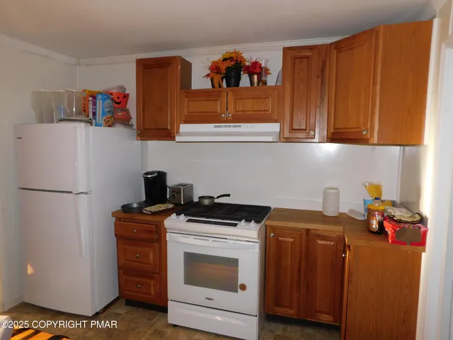 a view of a kitchen with fridge and wooden floor