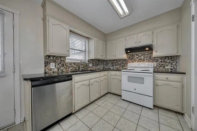 a kitchen with white cabinets appliances a sink and a window