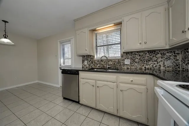 a kitchen with white cabinets appliances a sink and a window