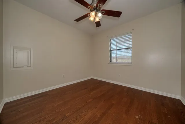 a view of an empty room with window and wooden floor