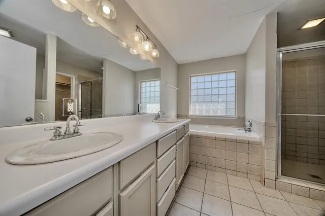 a bathroom with a sink double vanity granite tub shower and a mirror