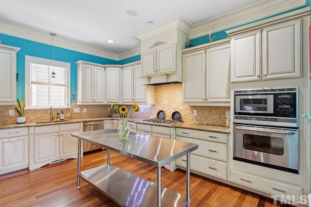 3100 Raymond Street Raleigh, NC 27607 - Photo 16 of 37 a kitchen with stainless steel appliances granite countertop a stove top oven a sink dishwasher and white cabinets with wooden floor