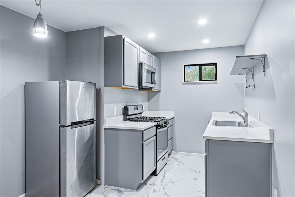 a kitchen with stainless steel appliances granite countertop a refrigerator a sink a stove a microwave and a refrigerator