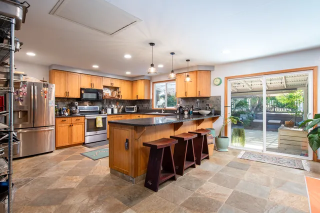 a kitchen with stainless steel appliances granite countertop a refrigerator a sink a stove and a refrigerator