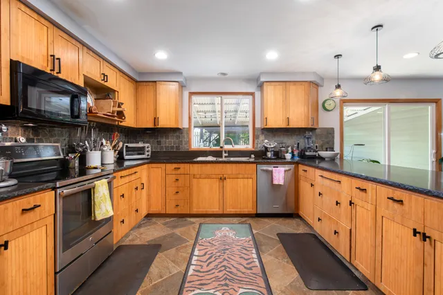a large kitchen with stainless steel appliances granite countertop a stove a sink and a microwave