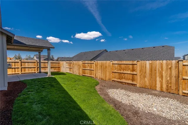 a view of a backyard with large trees and wooden fence