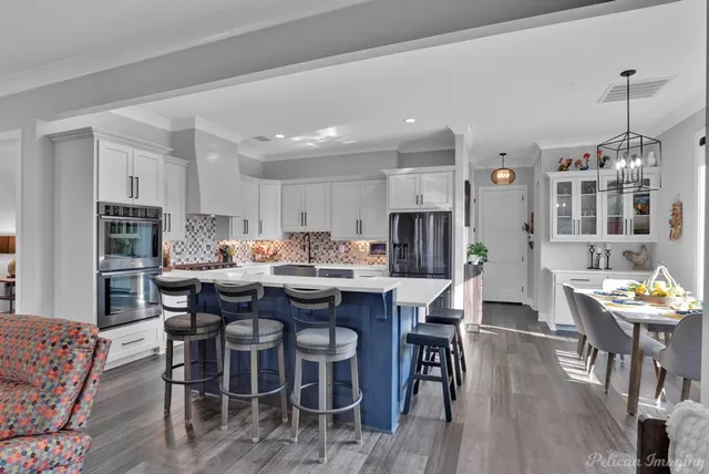 a large white kitchen with lots of counter space a sink appliances and dining table