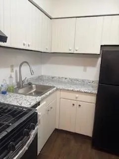 a kitchen with granite countertop a sink a stove and cabinets