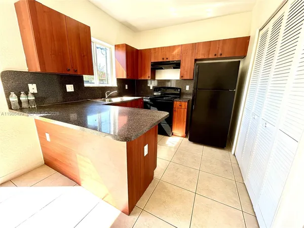 a kitchen with stainless steel appliances granite countertop a refrigerator a stove a sink and dishwasher with wooden cabinets