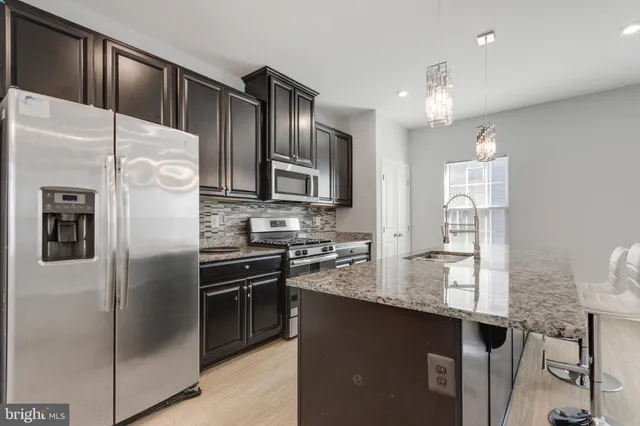 a kitchen with granite countertop stainless steel appliances cabinets a sink and a counter top space