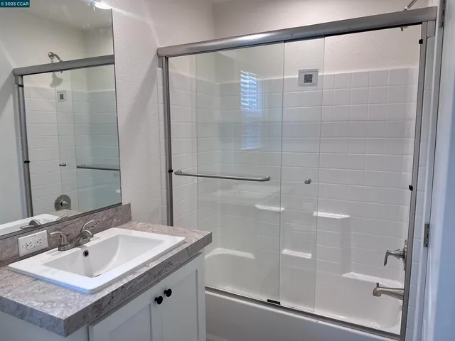 a bathroom with a shower sink vanity and mirror