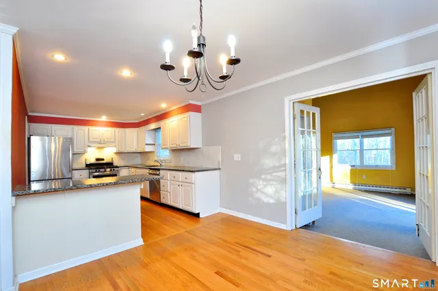 a kitchen with stainless steel appliances granite countertop wooden floors and wide window