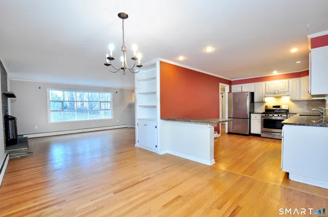 a view of a kitchen with furniture a ceiling fan and wooden floor