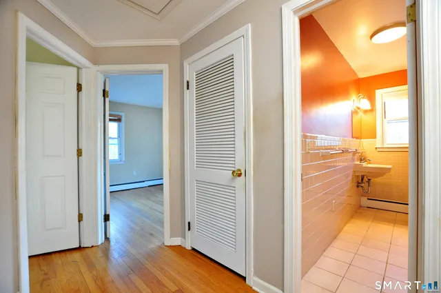 a view of a hallway with wooden floor a bathroom and a sink