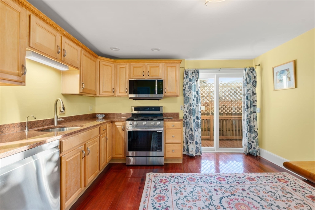 39 Lothrop Street, Unit 1 Boston, MA 02135 - Photo 4 of 19 a kitchen with stainless steel appliances granite countertop a stove top oven a sink dishwasher a dining table and chairs with wooden floor
