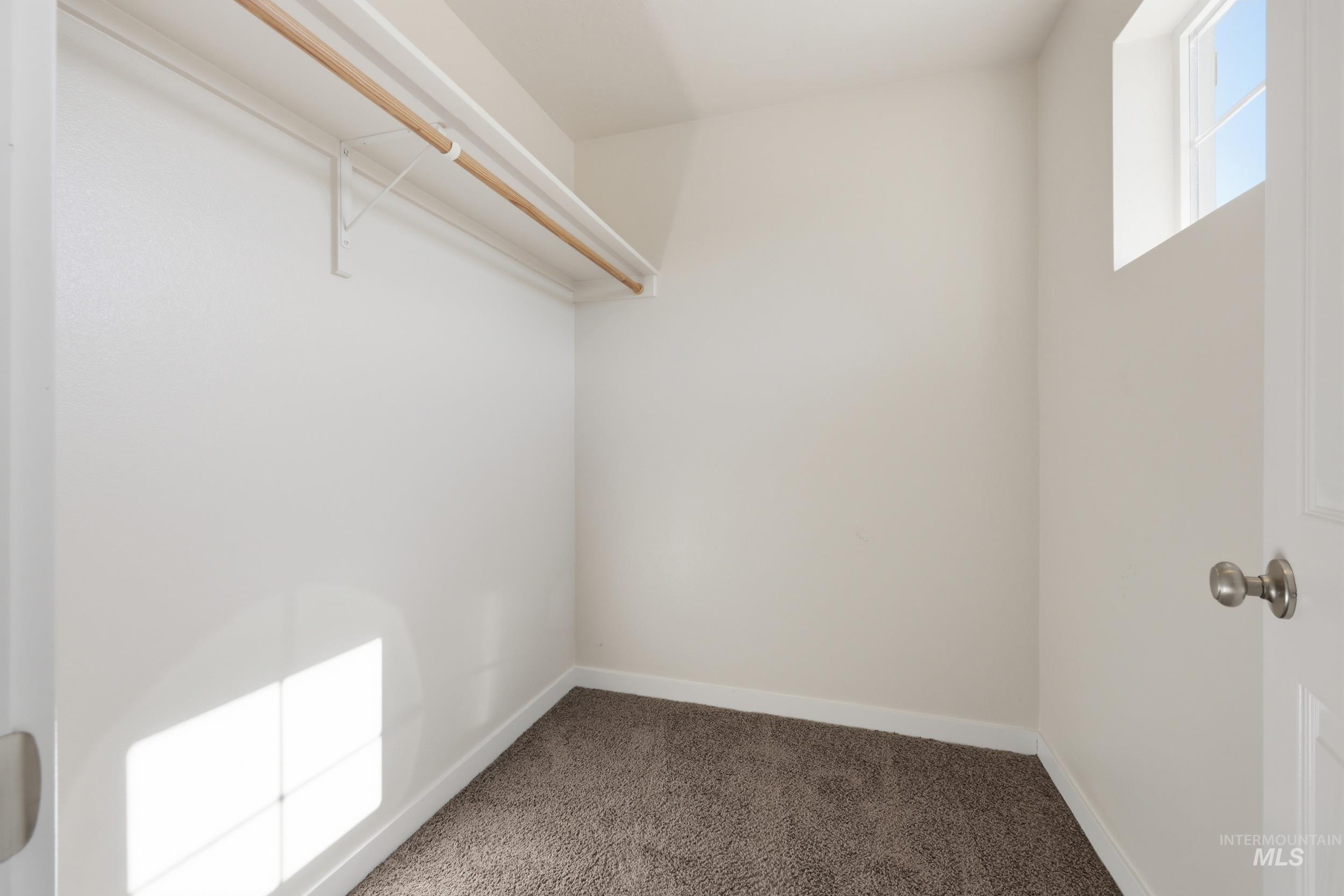 4855 South Chex Way Boise, ID 83709 - Photo 22 of 47 Walk-in closet featuring a high window, neutral wall paint, and a wood hanging rod with white shelving