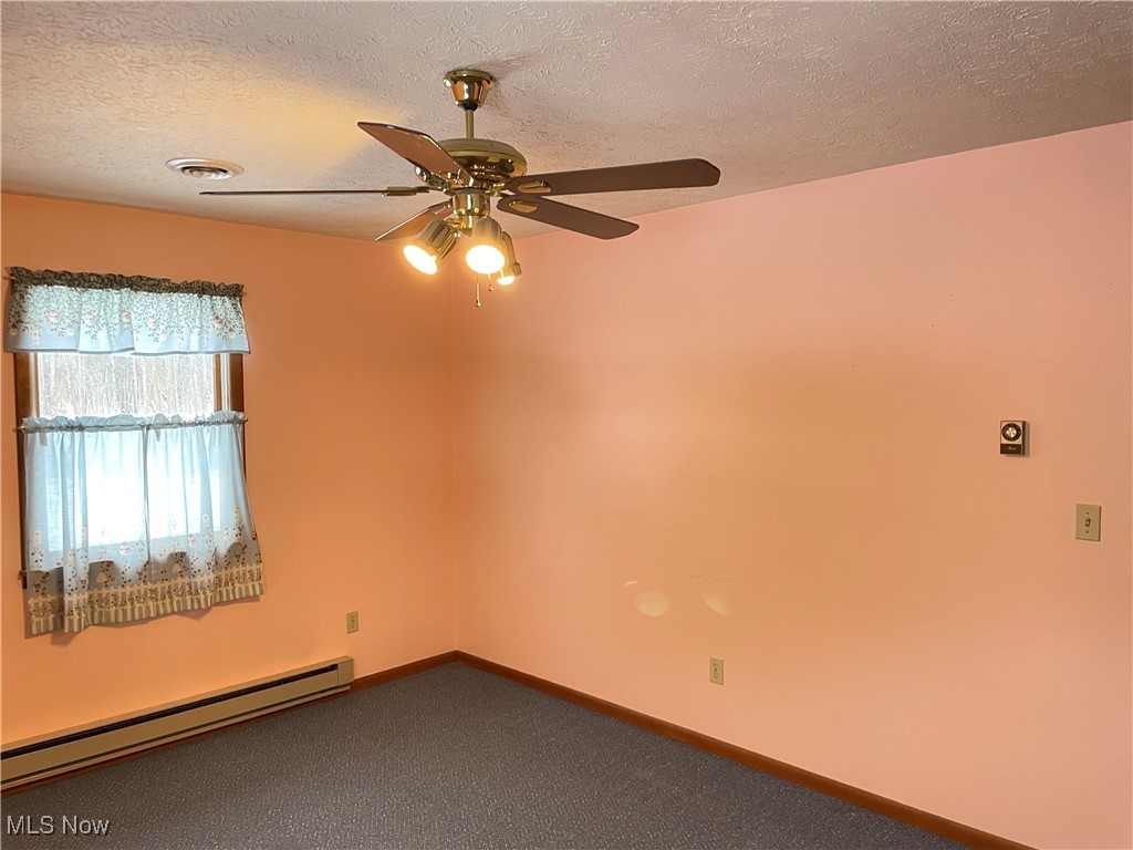 1381 Robb Road Conneaut, OH 44030 - Photo 23 of 50 Carpeted spare room with a baseboard heating unit, a textured ceiling, and a ceiling fan