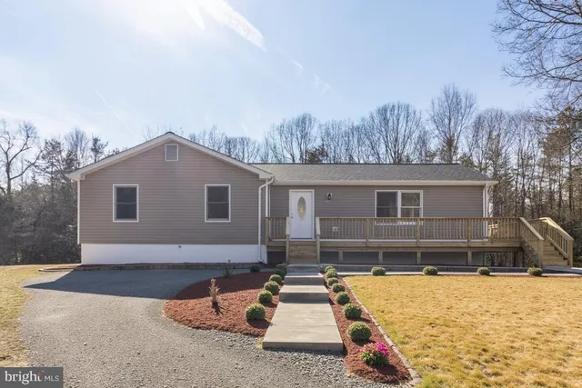 a front view of house with yard and trees in the background