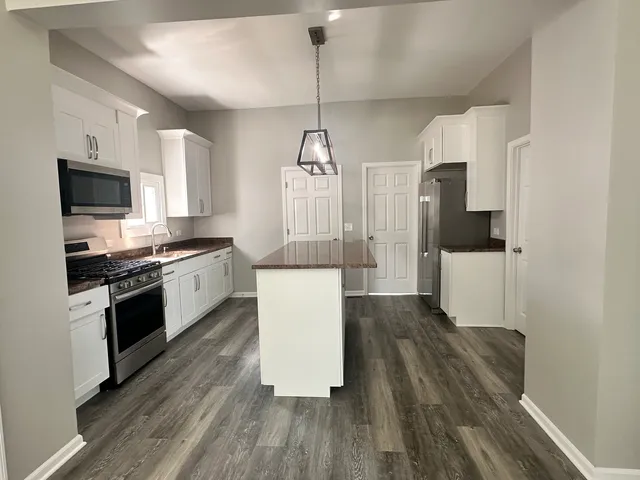 a kitchen with stainless steel appliances a refrigerator a stove a sink dishwasher and a oven with wooden floor