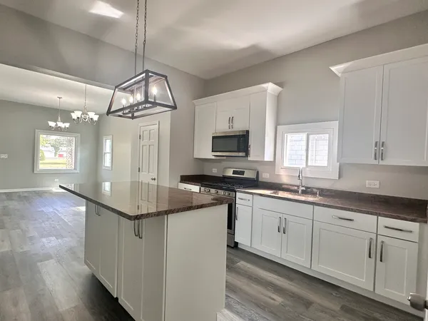 a kitchen with kitchen island granite countertop a sink cabinets and stainless steel appliances