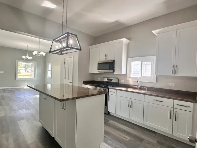 a kitchen with kitchen island granite countertop a sink cabinets and stainless steel appliances