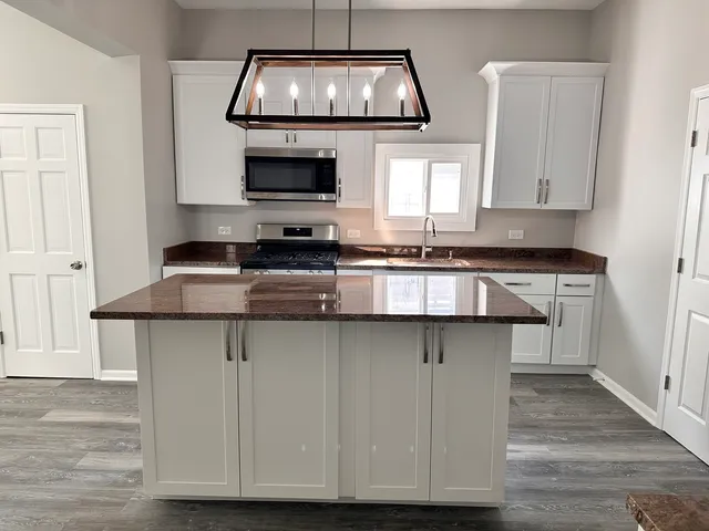 a kitchen with stainless steel appliances granite countertop a sink a stove and microwave