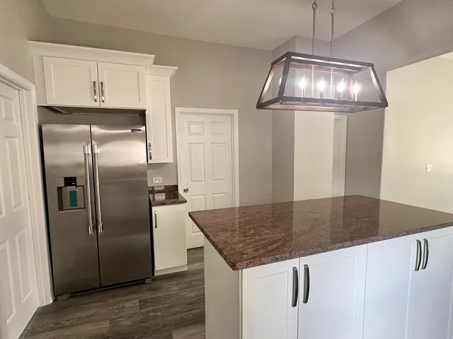 a kitchen with stainless steel appliances granite countertop a refrigerator a stove and a sink with wooden floor