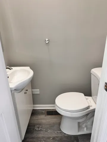 a white toilet sitting next to a white sink and vanity