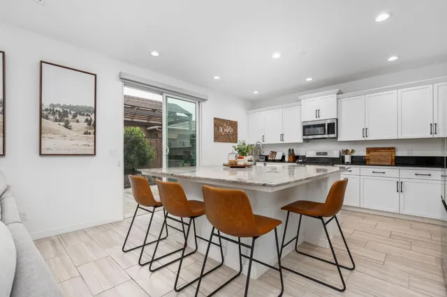 a kitchen with stainless steel appliances granite countertop a stove a sink a refrigerator with white cabinets and wooden floor