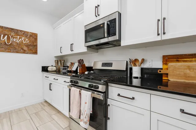 a kitchen with stainless steel appliances granite countertop white cabinets a stove a microwave and a sink