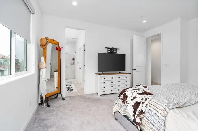 a bedroom with a bed and a flat tv screen on the dresser