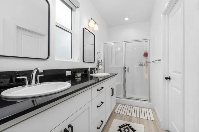 a bathroom with a double vanity sink a mirror and a shower