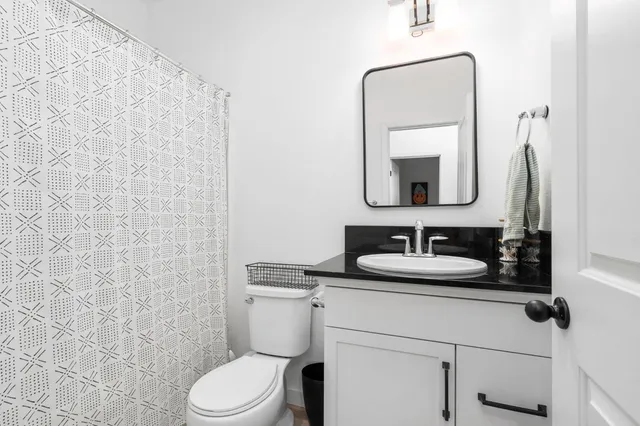 a bathroom with a toilet sink vanity and mirror