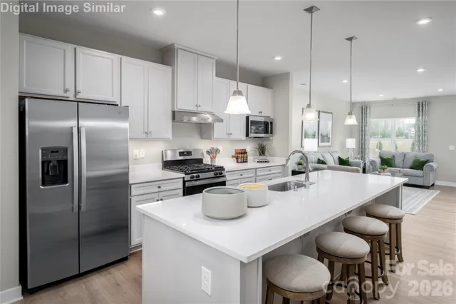 a kitchen with stainless steel appliances granite countertop a sink a stove a refrigerator and white cabinets with wooden floor