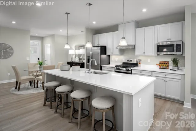 a kitchen with a dining table chairs stainless steel appliances and cabinets