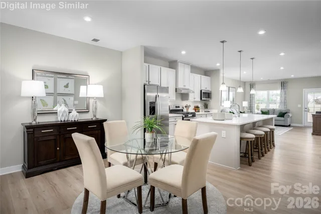 a dining room with kitchen island a dining table wooden floor and kitchen view