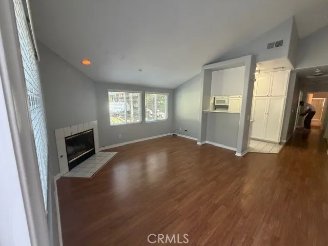 an empty room with windows fireplace and wooden floor