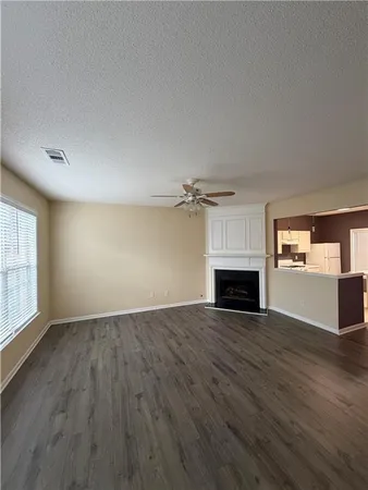 an empty room with windows fireplace and wooden floor