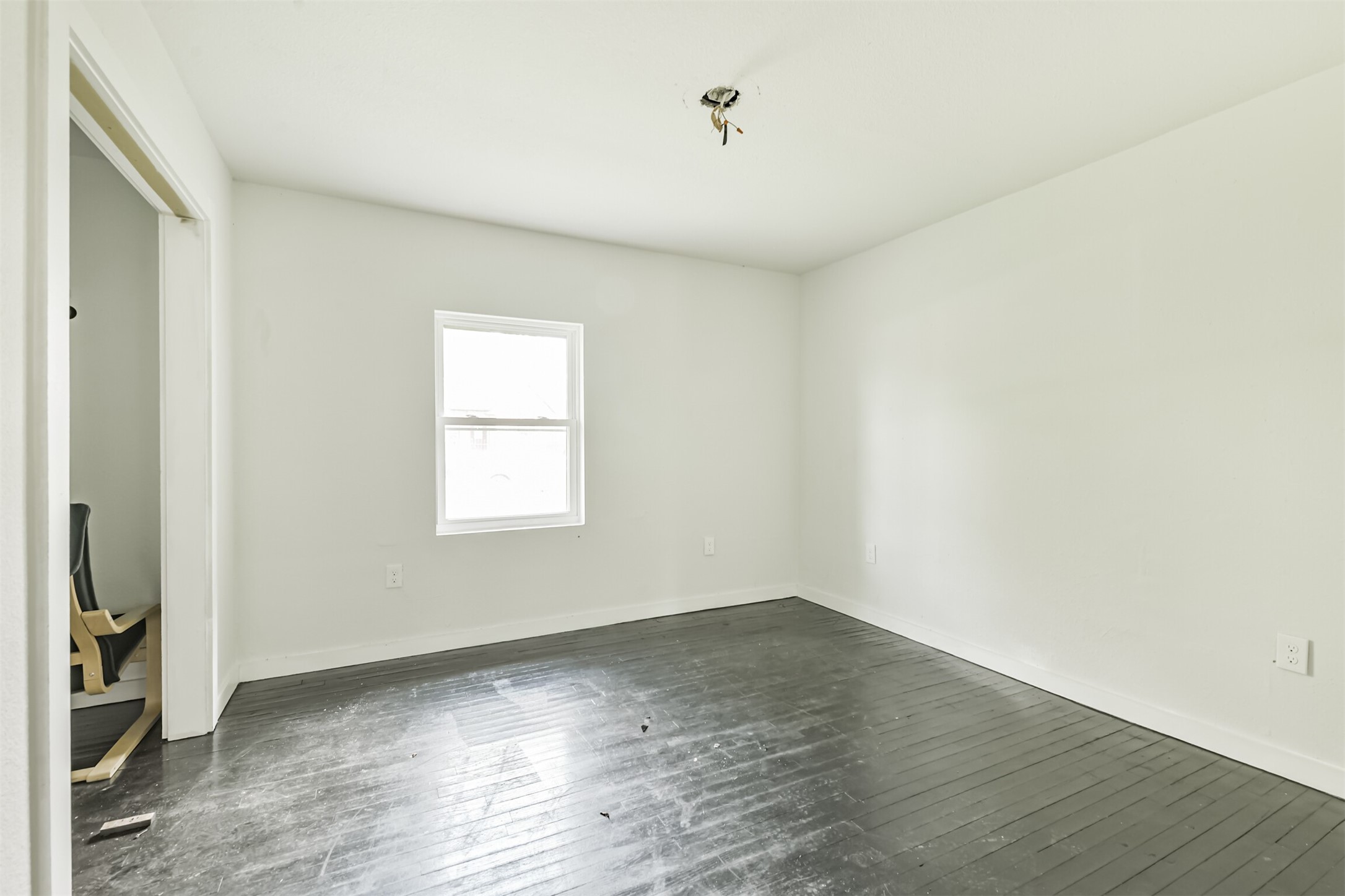 209 Leago Street Houston, TX 77022 - Photo 17 of 24 This room features white walls, a single window for natural light, and dark hardwood flooring. It's a blank canvas ready for personal touches.