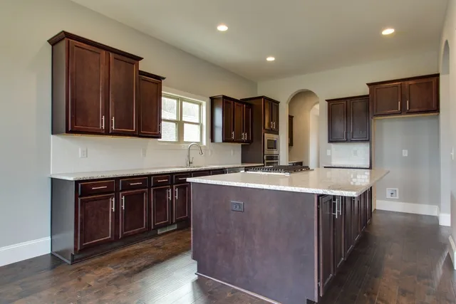 a kitchen with stainless steel appliances granite countertop wooden cabinets a stove and a sink