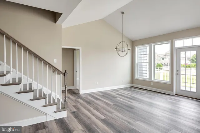 a kitchen with stainless steel appliances granite countertop a refrigerator a oven a sink a dining table and chairs with wooden floor